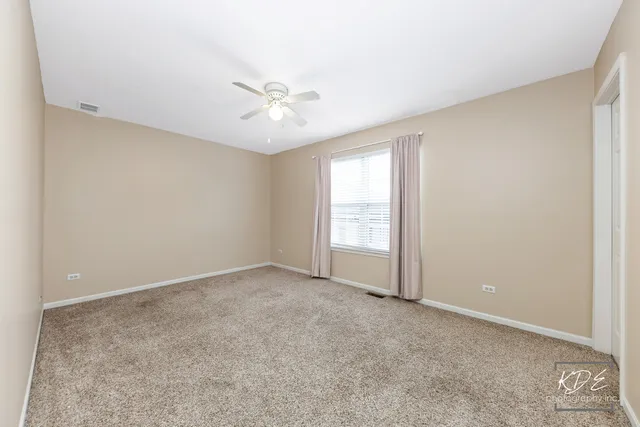 an empty room with a window and a ceiling fan