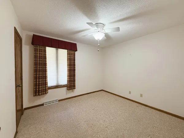 an empty room with a ceiling fan and windows