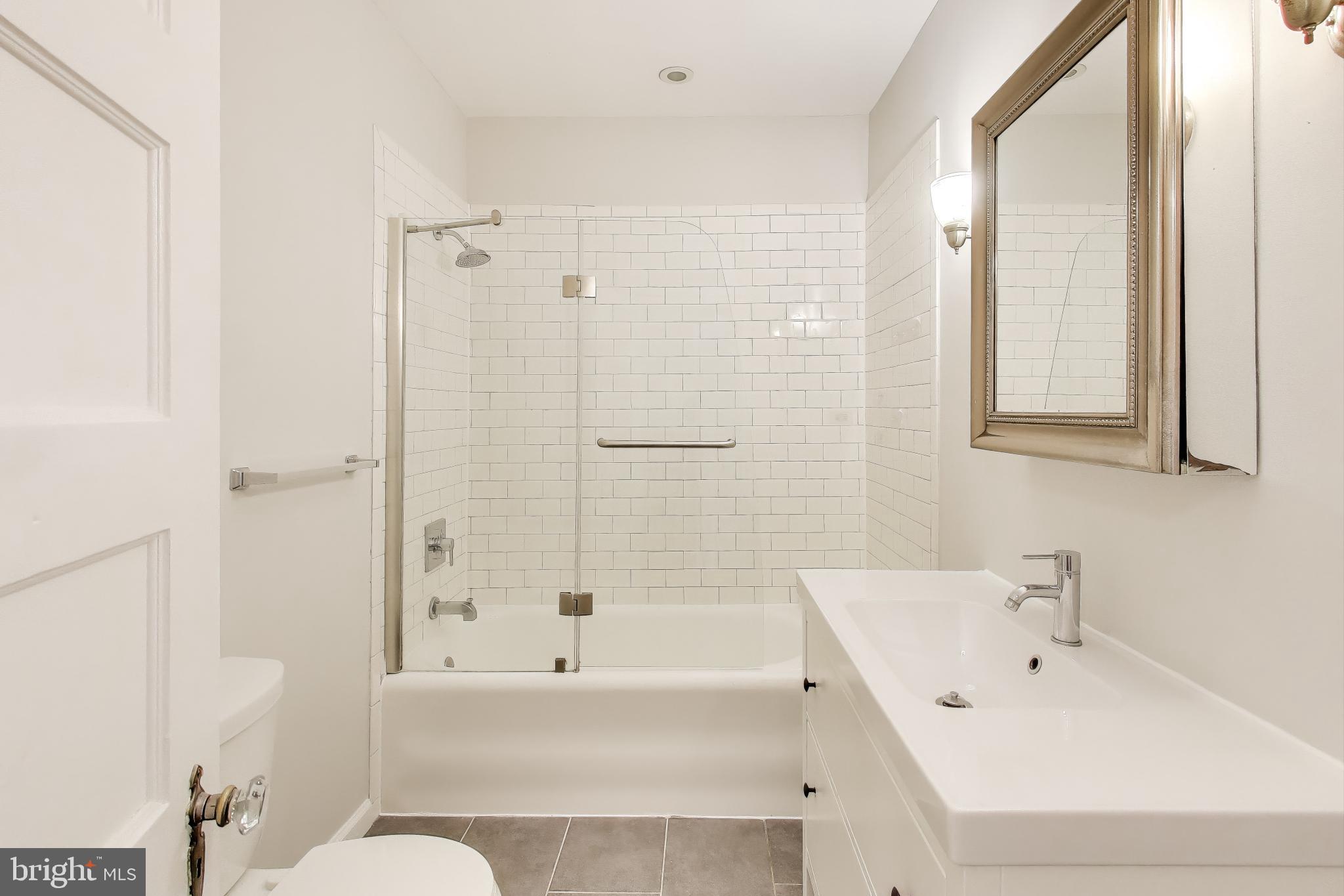 628 Madison Street Northwest Washington, DC 20011 - Photo 6 of 47 a bathroom with a bathtub a sink a toilet and a mirror