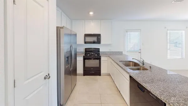 a kitchen with granite countertop stainless steel appliances a refrigerator and a sink