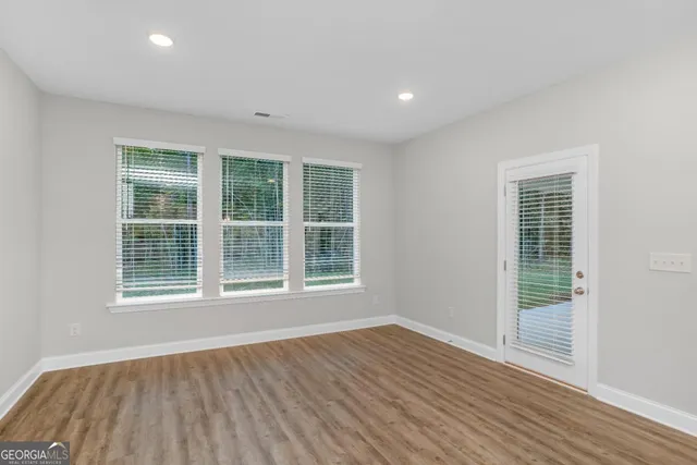 an empty room with wooden floor and windows