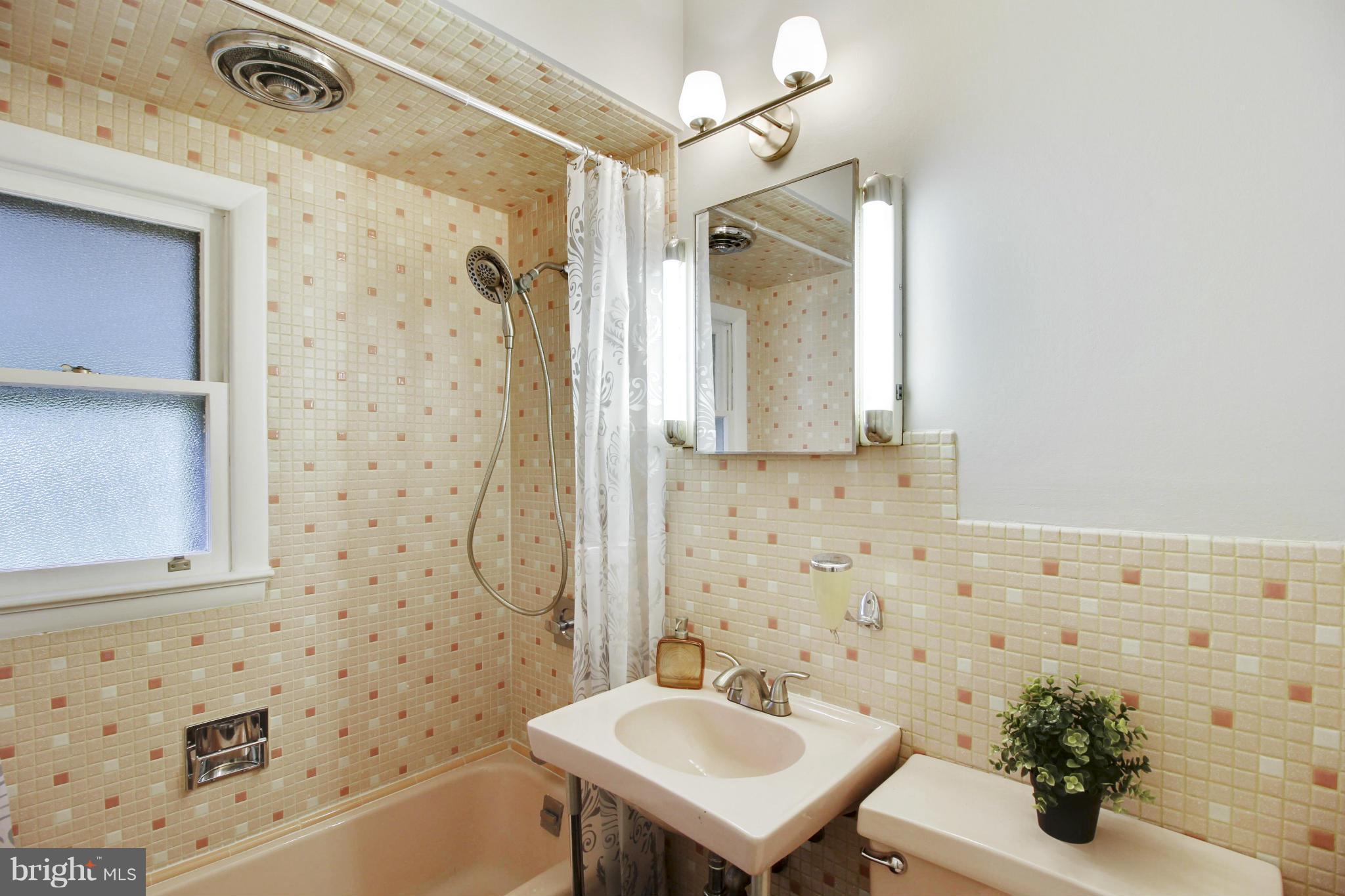 12128 Veirs Mill Road Silver Spring, MD 20906 - Photo 16 of 30 a bathroom with a sink a mirror a bathtub and shower