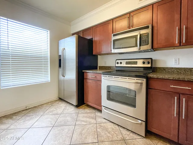 a kitchen with granite countertop wooden cabinets stainless steel appliances and a window