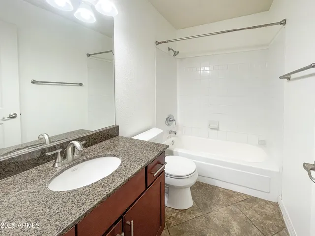 a bathroom with a granite countertop sink toilet mirror and bathtub