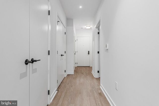 a view of a hallway with wooden floor and a bathroom