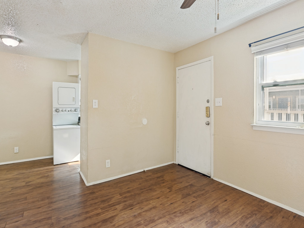 2401 Manor Road, Unit 218 Austin, TX 78722 - Photo 15 of 27 A compact living area with rich wood-look flooring and integrated laundry appliances for convenience.