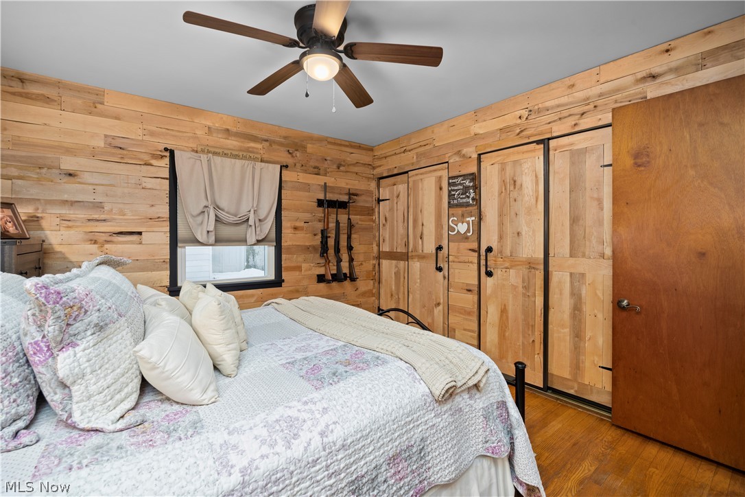 965 Gulf Road Elyria, OH 44035 - Photo 16 of 37 Bedroom featuring wooden walls, a ceiling fan, and light hardwood flooring, window, and double closets