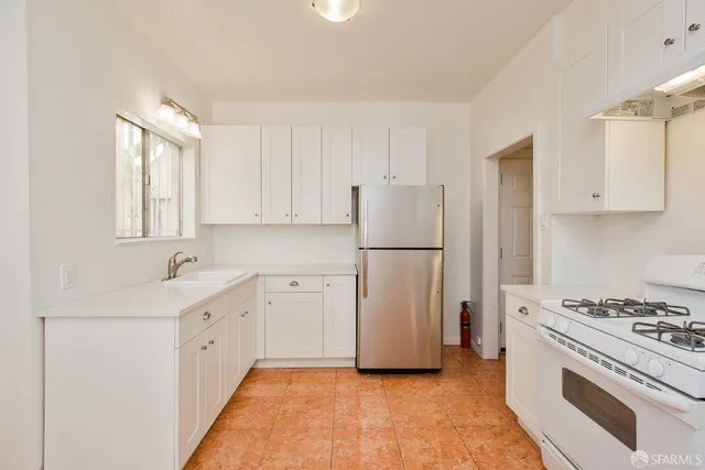 a kitchen with white cabinets and sink