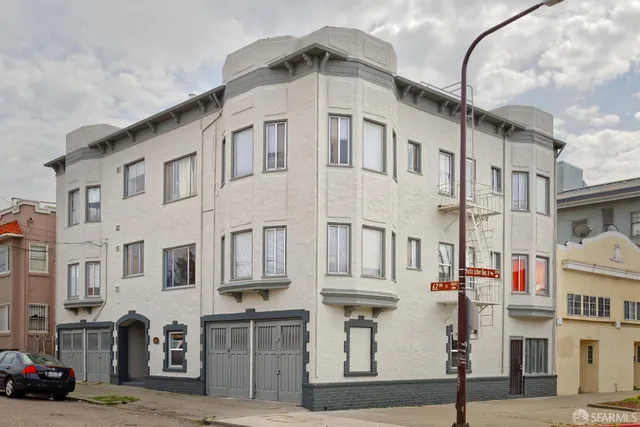 a front view of a building with lot of cars and trees