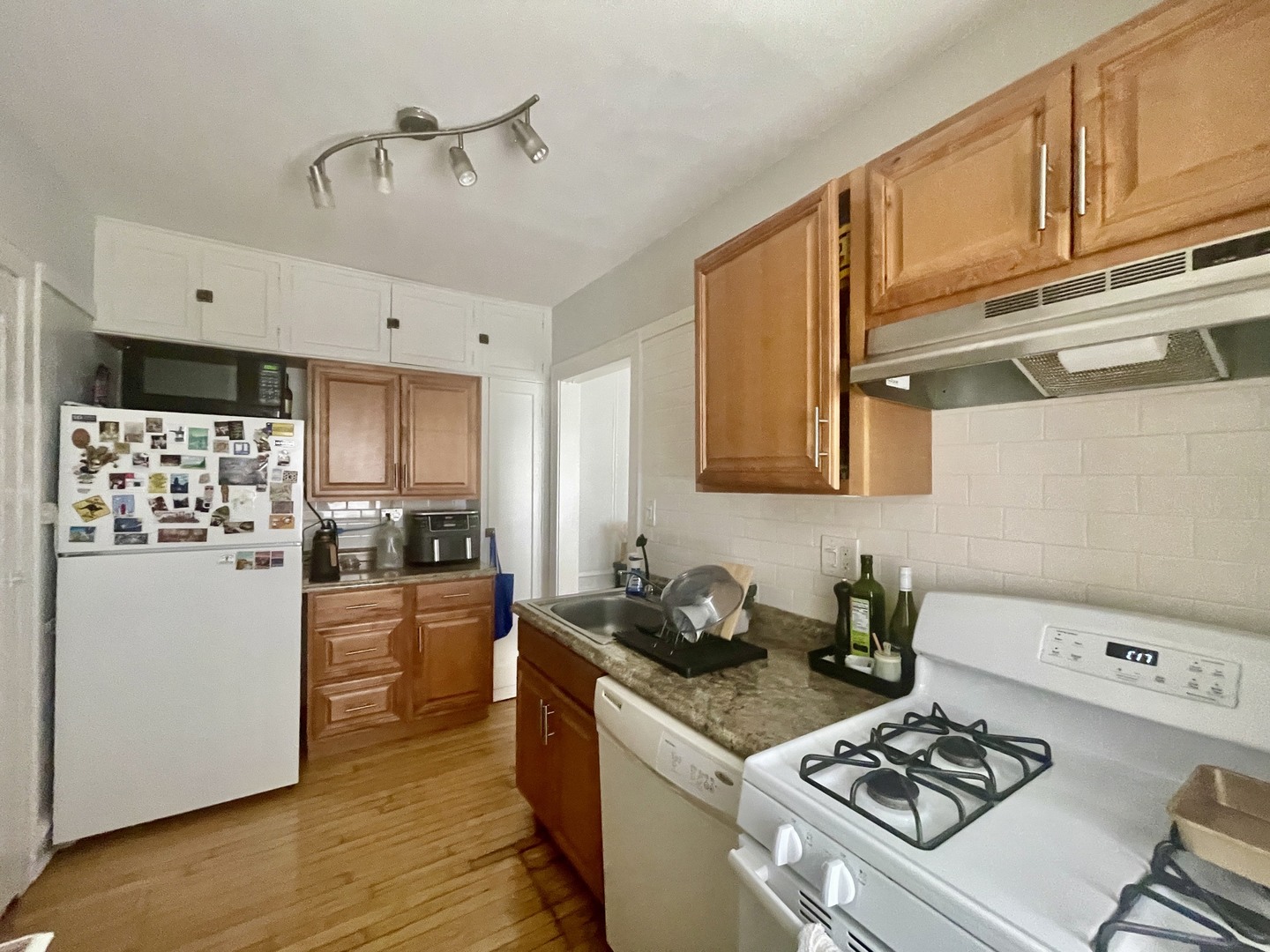 1112 Grove Street, Unit 1B Evanston, IL 60201 - Photo 6 of 14 a kitchen with stainless steel appliances a stove a sink a refrigerator wooden floor cabinets and dining table