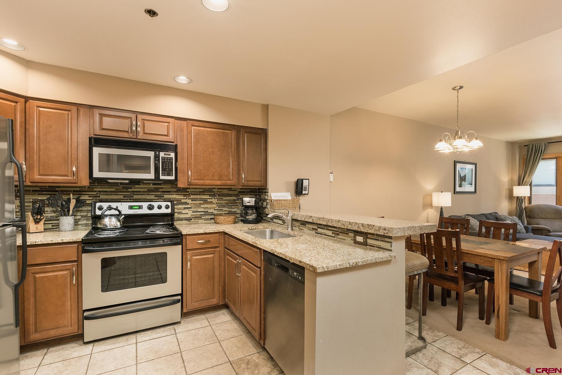 71 Needles Way, Unit 443 Durango, CO 81301 - Photo 7 of 26 a kitchen with a stove a sink a microwave and a dining table