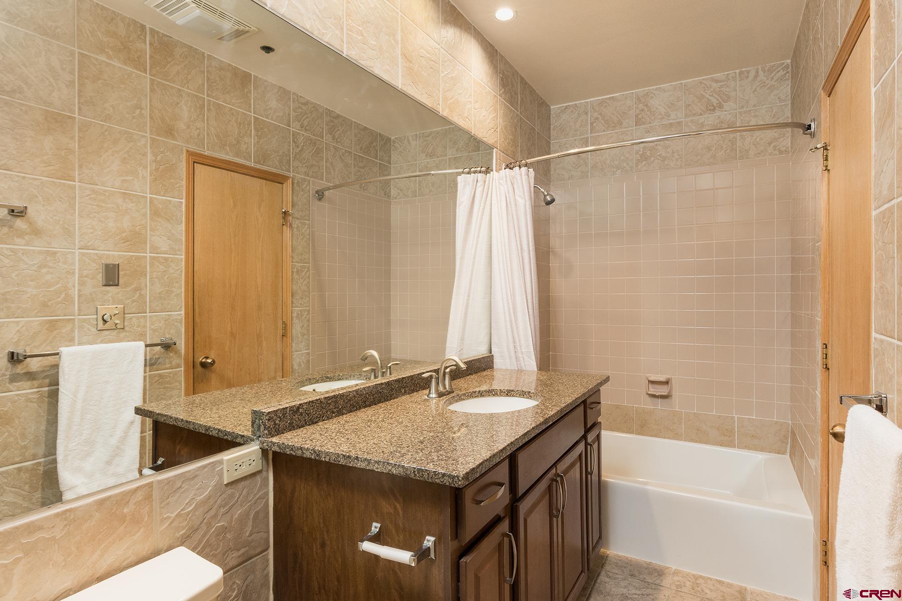 71 Needles Way, Unit 443 Durango, CO 81301 - Photo 10 of 26 a bathroom with a granite countertop sink a toilet and shower
