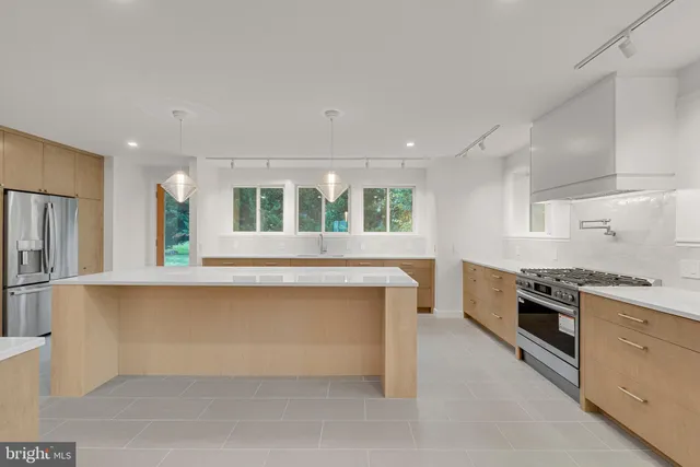 a large white kitchen with stainless steel appliances granite countertop a stove and a sink