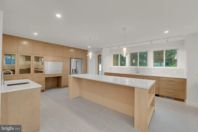 a large kitchen with kitchen island a sink a stove a refrigerator and white cabinets