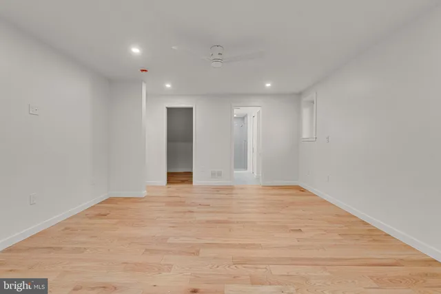 a view of an empty room with wooden floor and window