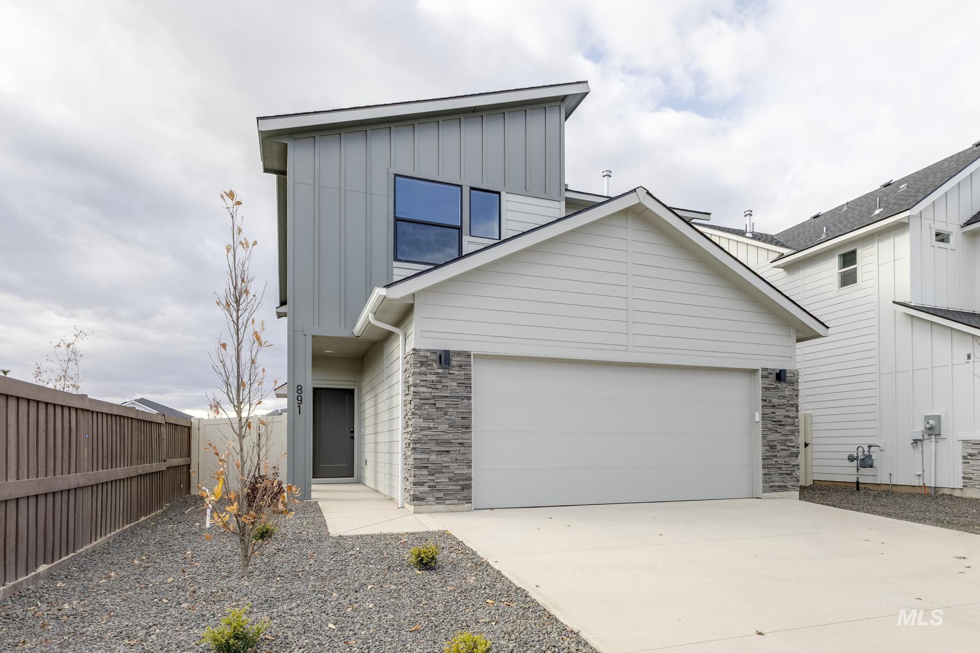 View of front facade with board and batten siding, concrete driveway, stone siding, and an attached garage