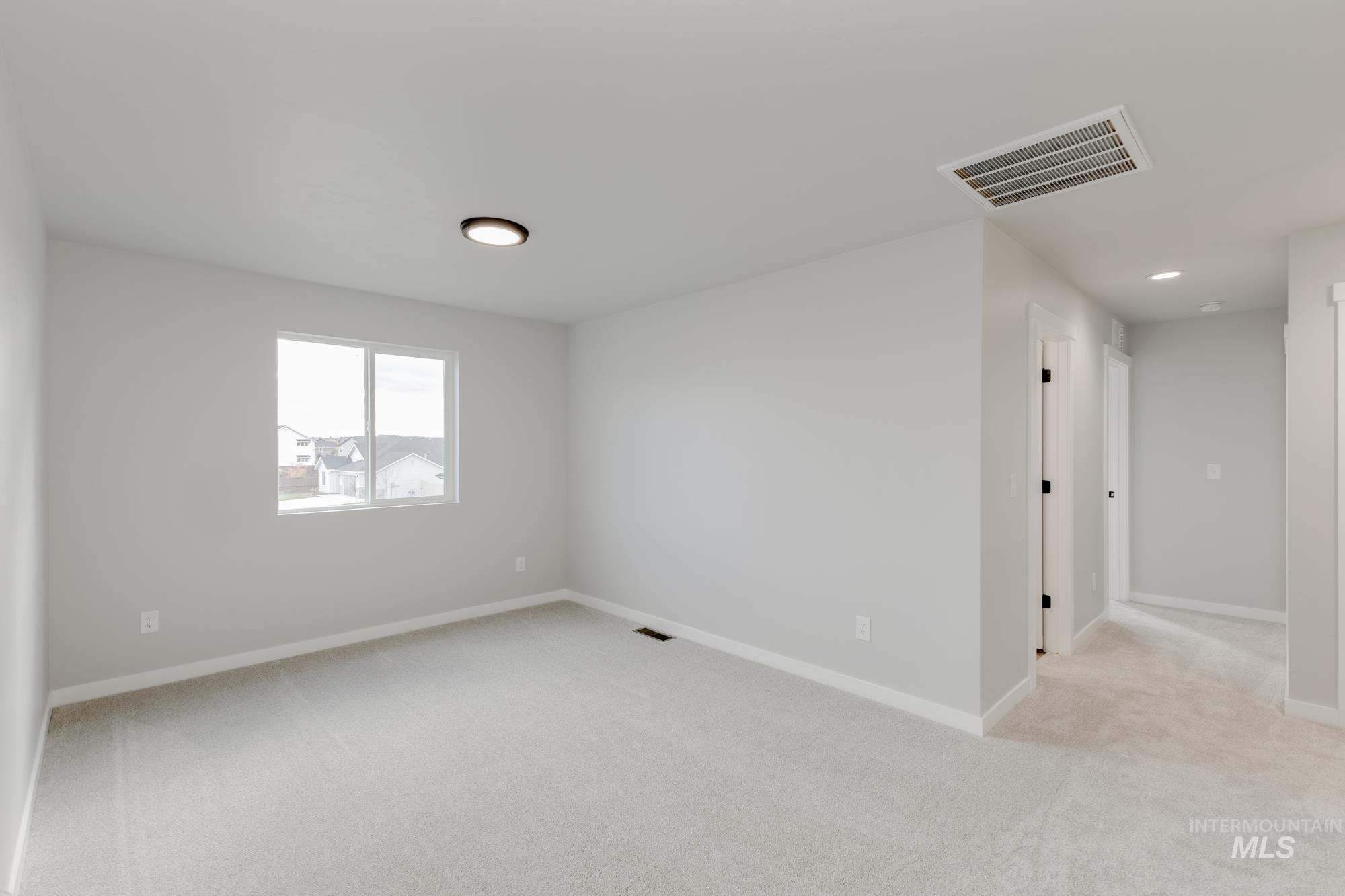 891 North Mirror Creek Way Meridian, ID 83642 - Photo 12 of 20 Empty room with light carpet and baseboards