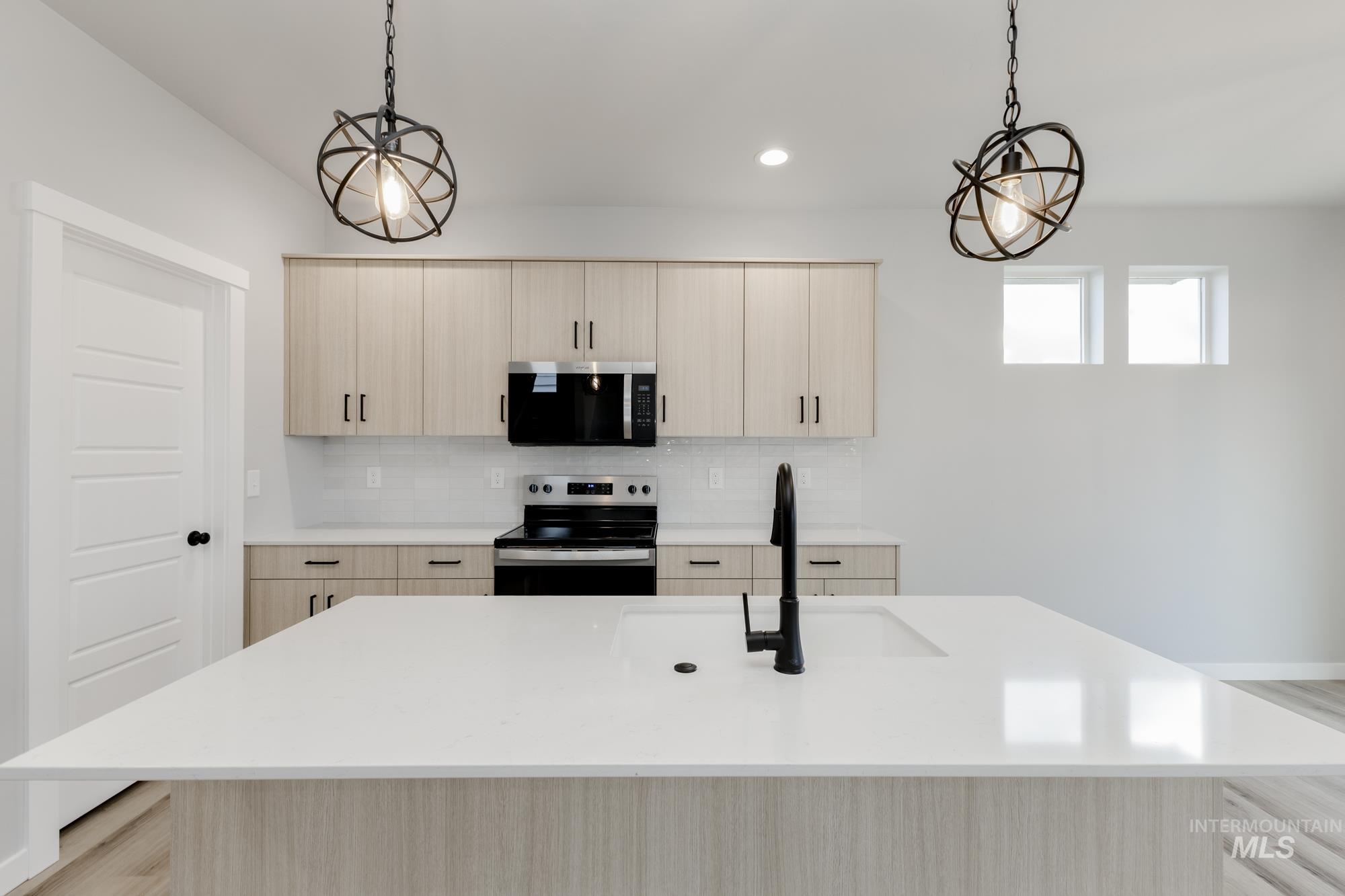 891 North Mirror Creek Way Meridian, ID 83642 - Photo 4 of 20 Kitchen featuring light brown cabinetry, a center island with sink, stainless steel appliances, light stone counters, and hanging light fixtures