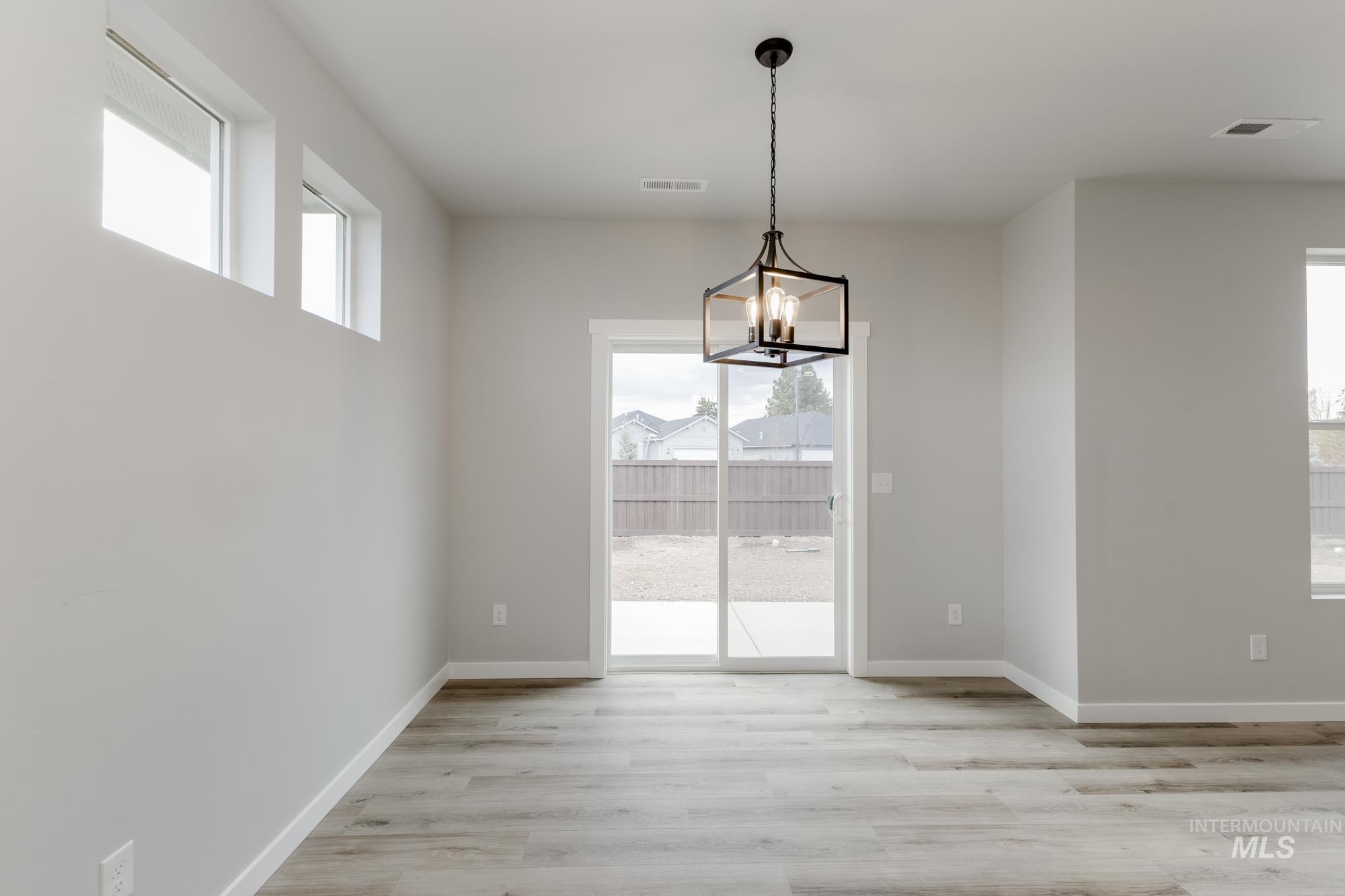 891 North Mirror Creek Way Meridian, ID 83642 - Photo 7 of 20 Unfurnished dining area with plenty of natural light, light wood-style floors, and a chandelier