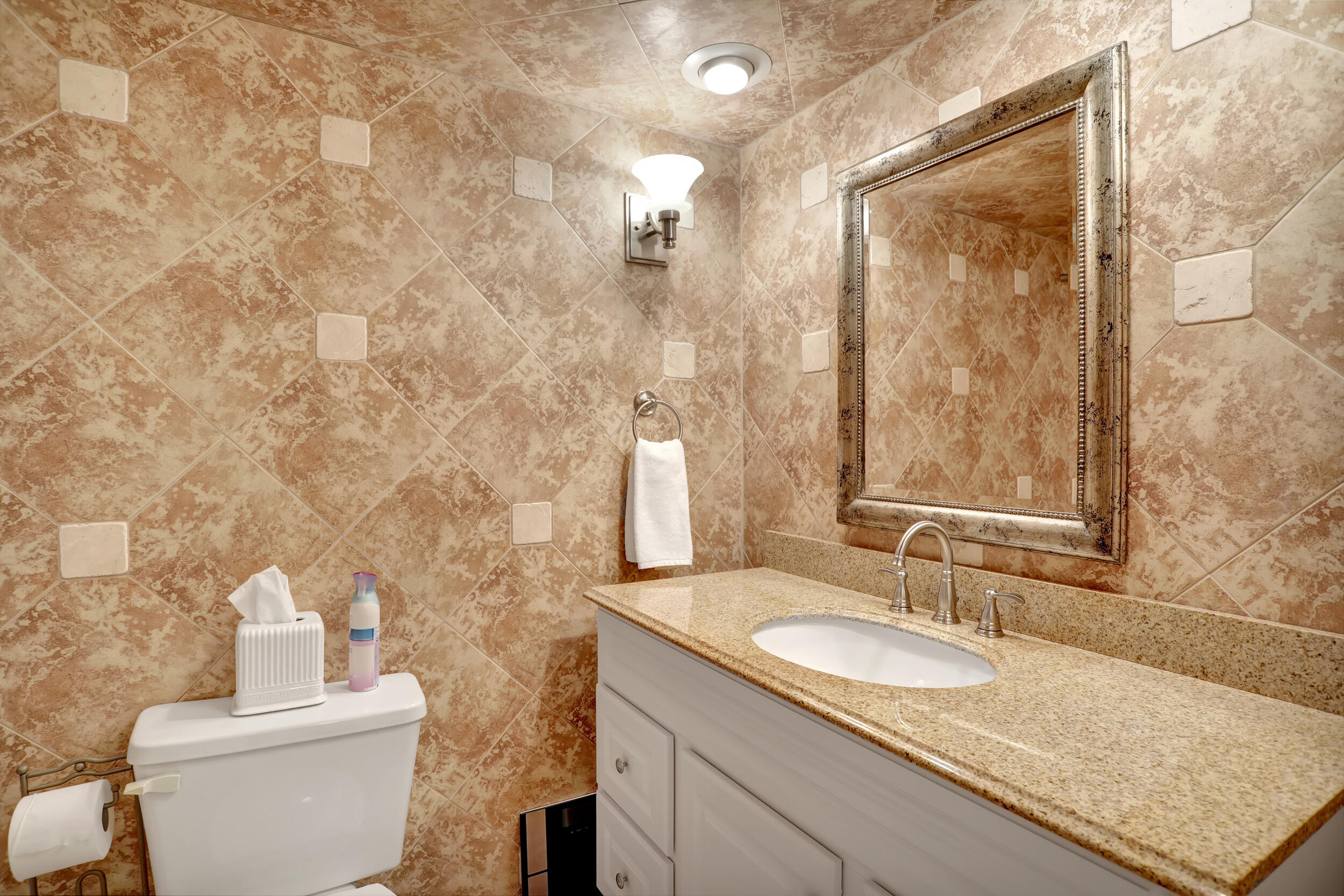 3001 South Course Drive, Unit 508 Pompano Beach, FL 33069 - Photo 22 of 36 a bathroom with a granite countertop sink a toilet and a mirror