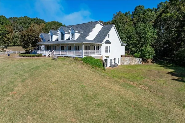 a view of a house with a big yard and large trees