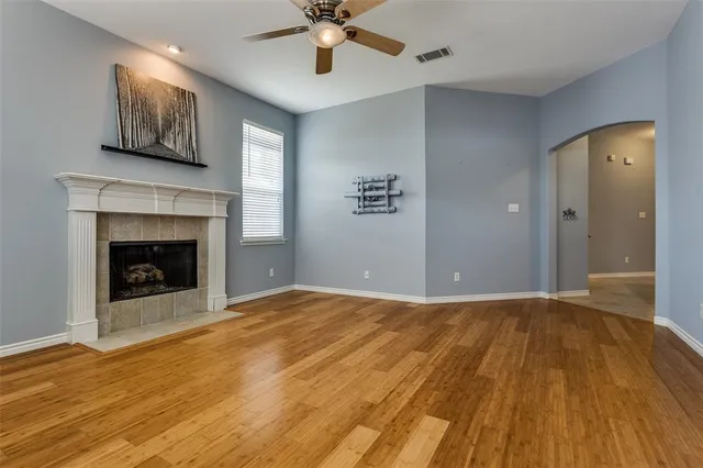 a view of an empty room with wooden floor and a fireplace