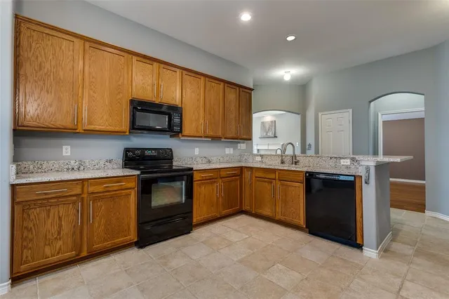 a kitchen with stainless steel appliances granite countertop wooden cabinets a stove top oven a granite counter top and a refrigerator