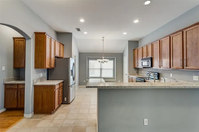 a kitchen with stainless steel appliances granite countertop a sink a stove and a refrigerator