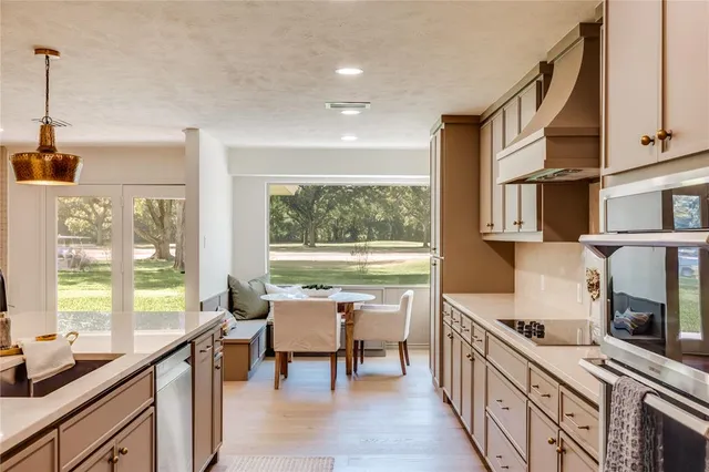a kitchen with stainless steel appliances kitchen island a table chairs in it and wooden floors