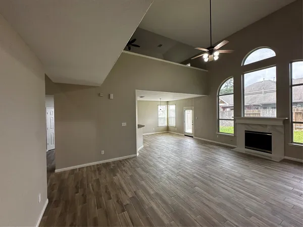 an empty room with wooden floor fan and windows