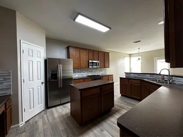 a large kitchen with stainless steel appliances granite countertop a stove refrigerator and a stove