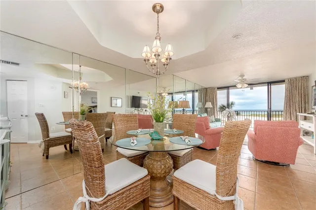 a view of a dining room with furniture a chandelier and large windows