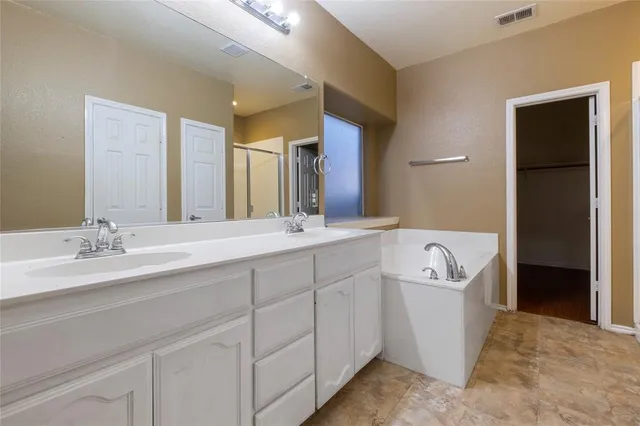 a spacious bathroom with a tub sink and mirror