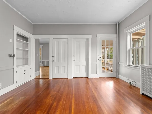 a view of an empty room with wooden floor and a window