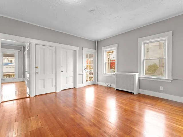 a view of an empty room with window and wooden floor