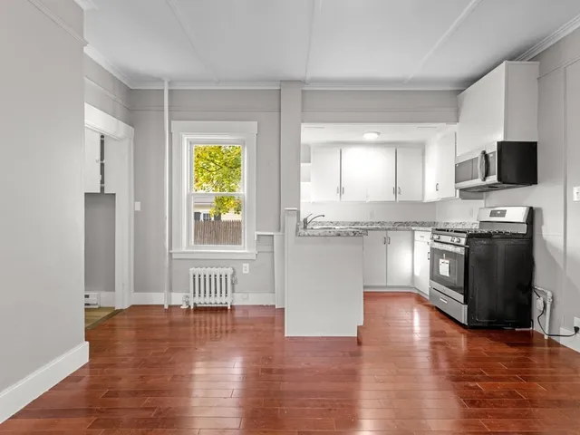 a kitchen with stainless steel appliances granite countertop a stove top oven a sink and a granite counter tops with wooden floors