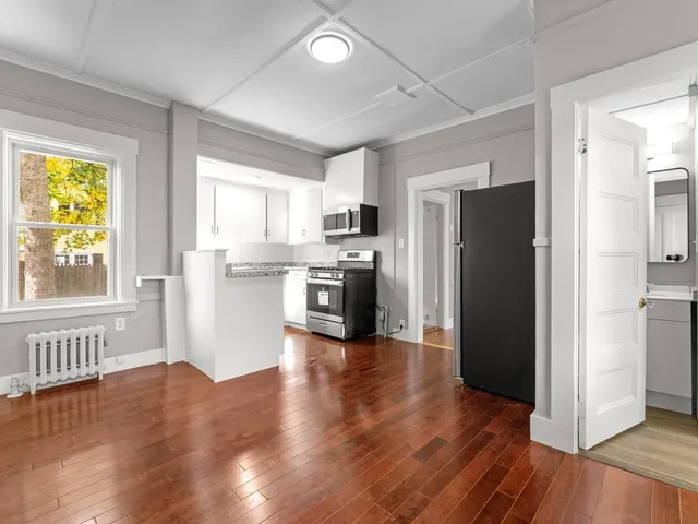 a kitchen with a refrigerator a stove top oven and wooden floors