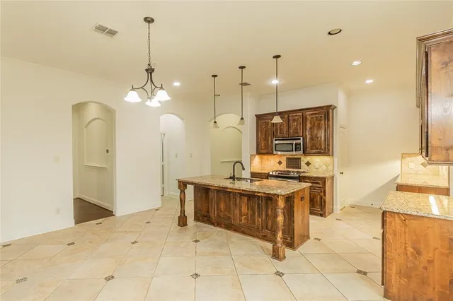 a large kitchen with kitchen island a stove a sink a center island and a wooden floor
