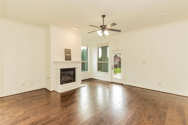 an empty room with windows fireplace and a kitchen view