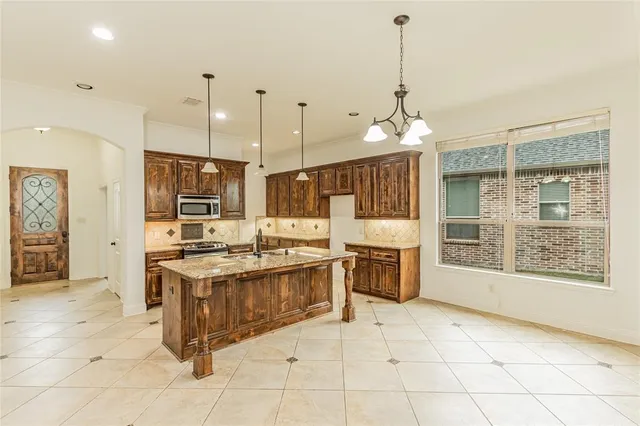 a kitchen with stainless steel appliances granite countertop a stove top oven a sink dishwasher and a refrigerator