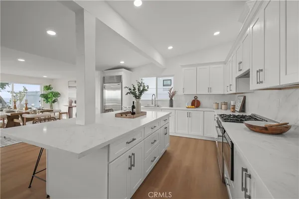 a large kitchen with kitchen island a stove a sink a dining table and chairs with wooden floor