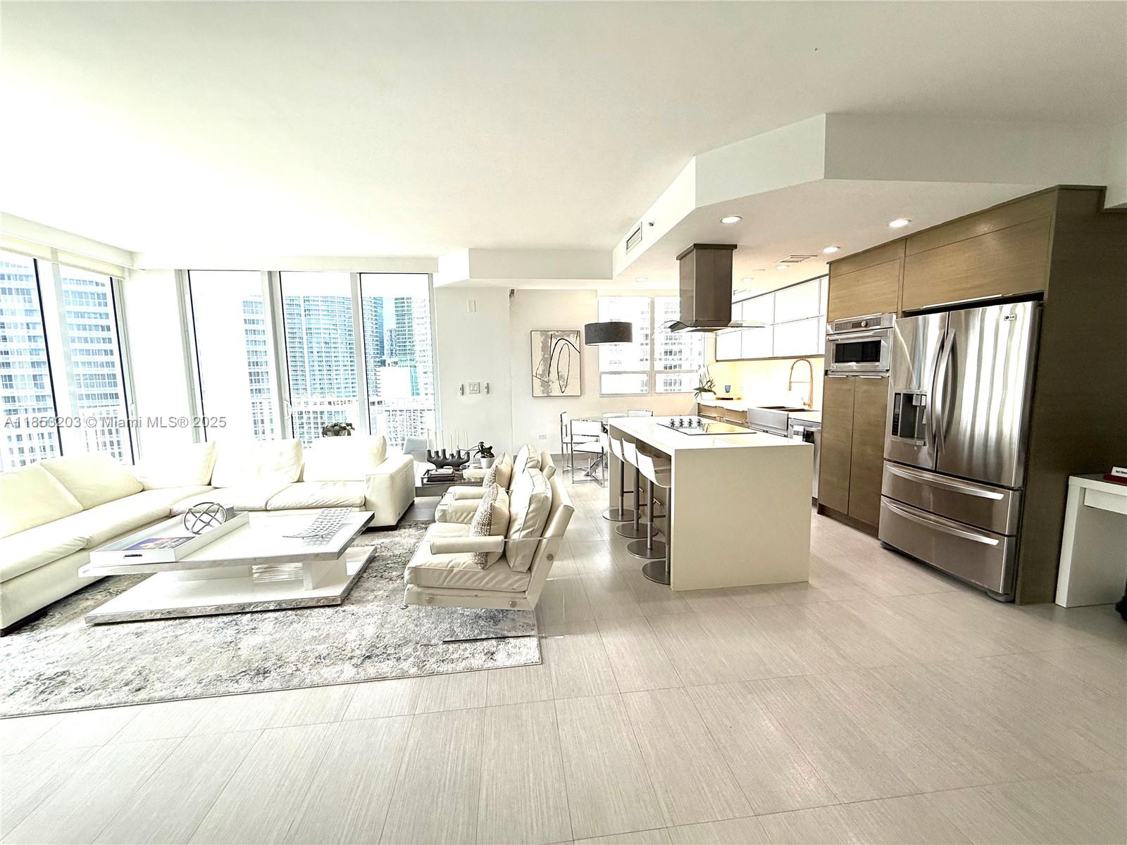 801 Brickell Key Boulevard, Unit 2402 Miami, FL 33131 - Photo 6 of 37 a living room with stainless steel appliances kitchen island granite countertop a refrigerator a stove and a sink with couches