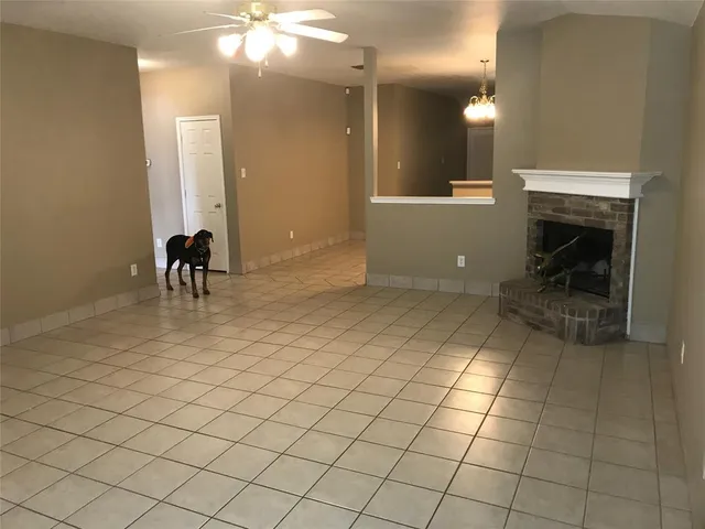 an empty room with a fireplace and chandelier fan