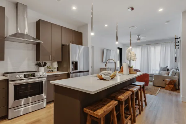 a kitchen with a stove a refrigerator and a dining table with wooden floor