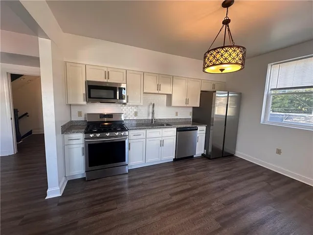 a kitchen with stainless steel appliances a refrigerator a stove top oven a sink dishwasher and microwave with wooden floor