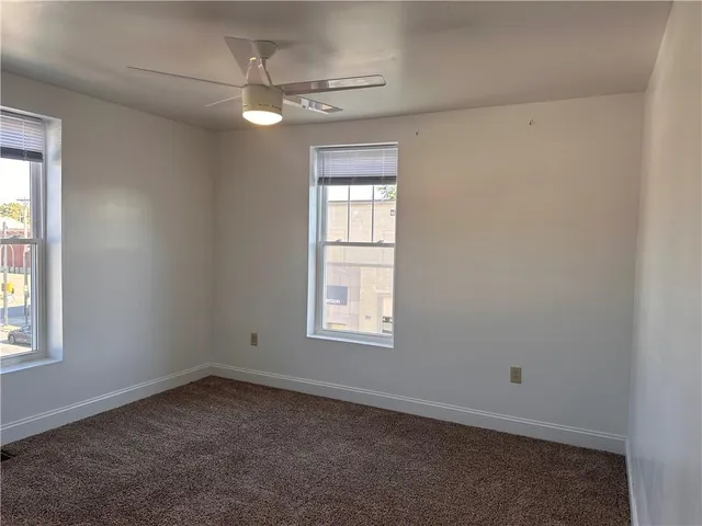 an empty room with a window and a fan