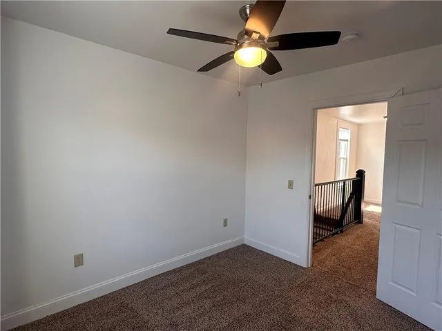 an empty room with a chandelier fan and a window