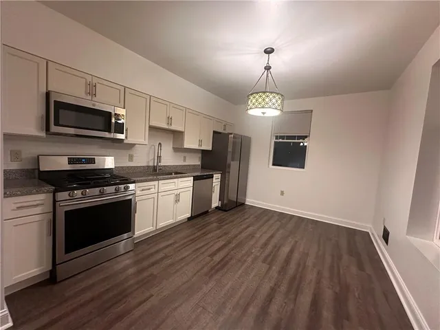 a kitchen with stainless steel appliances granite countertop a stove top oven a sink dishwasher and a microwave oven on the wooden floor