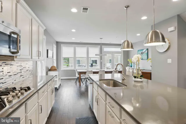 a large kitchen with stainless steel appliances kitchen island granite countertop a large stove a sink a oven and a dining table with wooden floor