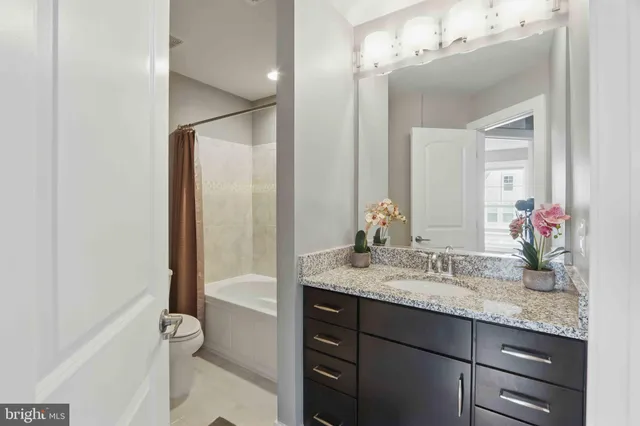 a bathroom with a granite countertop sink mirror and a bathtub